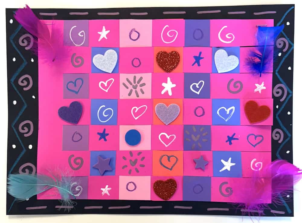 Colorful patchwork art with pink, purple, and red squares decorated with hearts, stars, and spirals. Features vibrant feathers along the edges, resembling a paper weaving masterpiece.